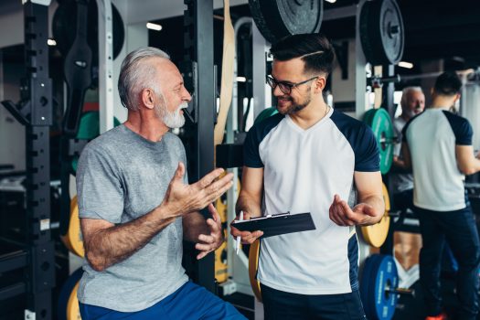 Senior man exercising in gym with his personal trainer.