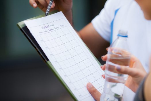 Fitness plan. Sports trainer amounts to workout plan close-up.